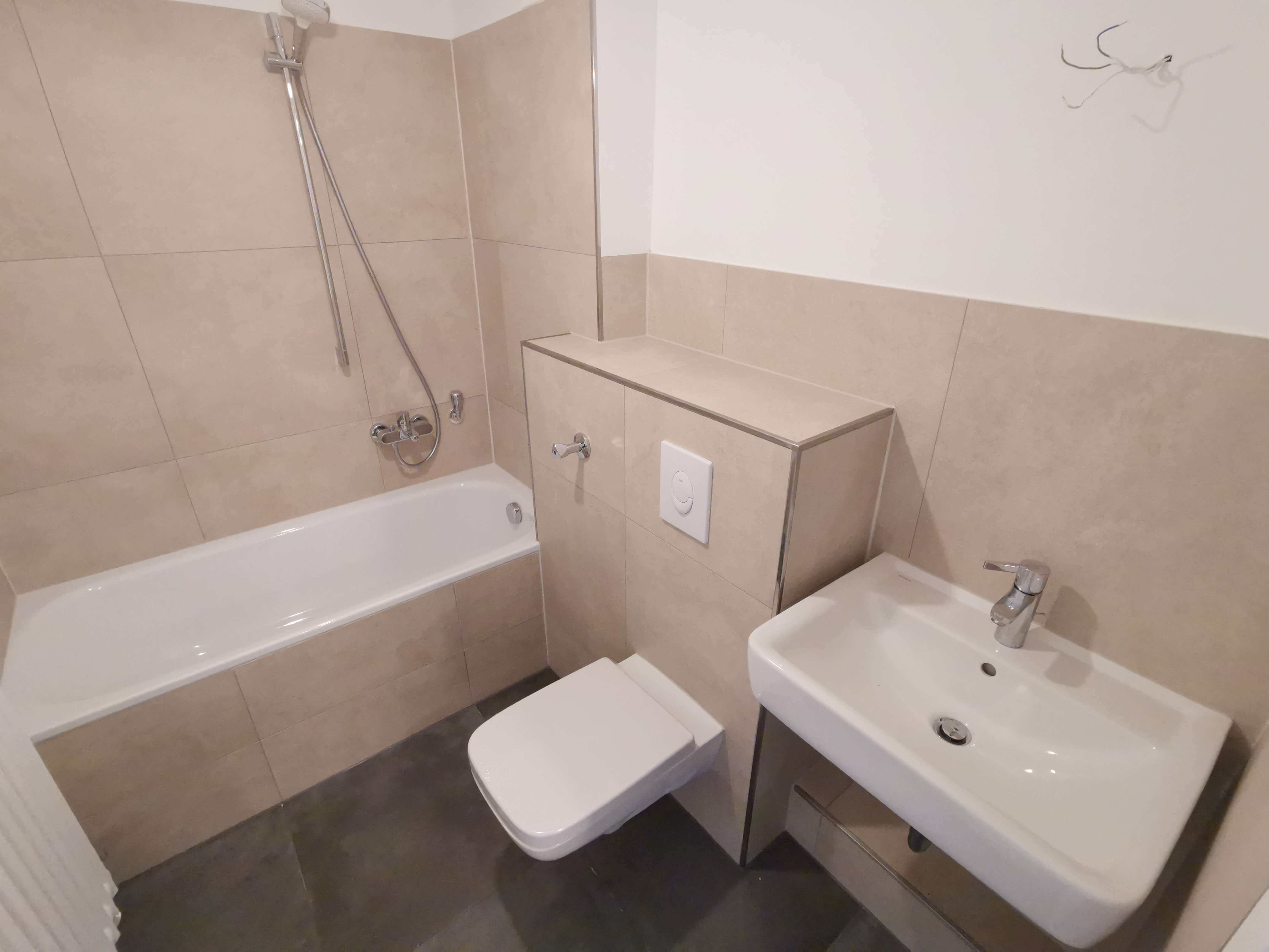 Modern saniertes Badezimmer mit Duschabtrennung und neuen Fliesen